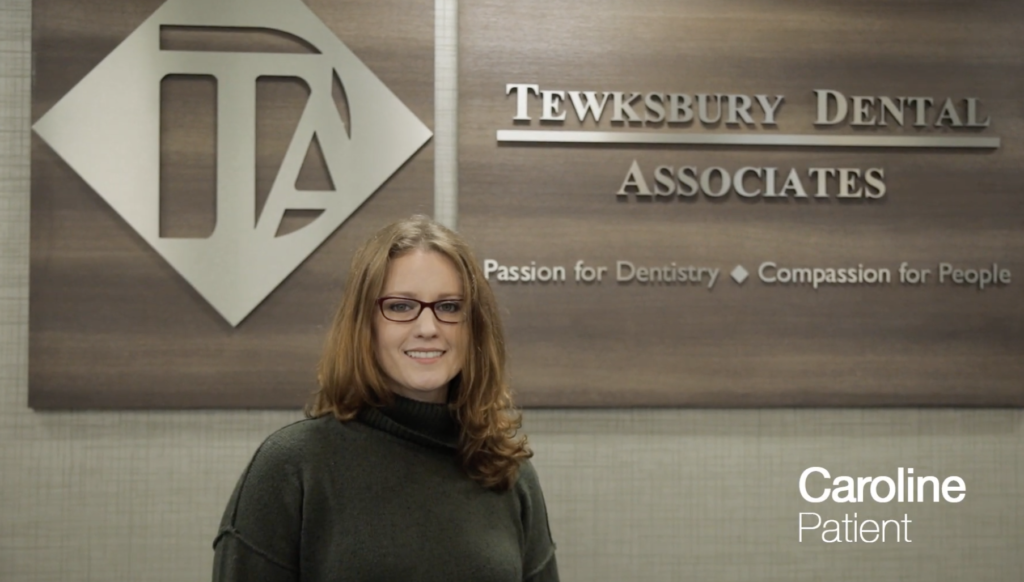 Woman standing in front of tewksbury dental sign