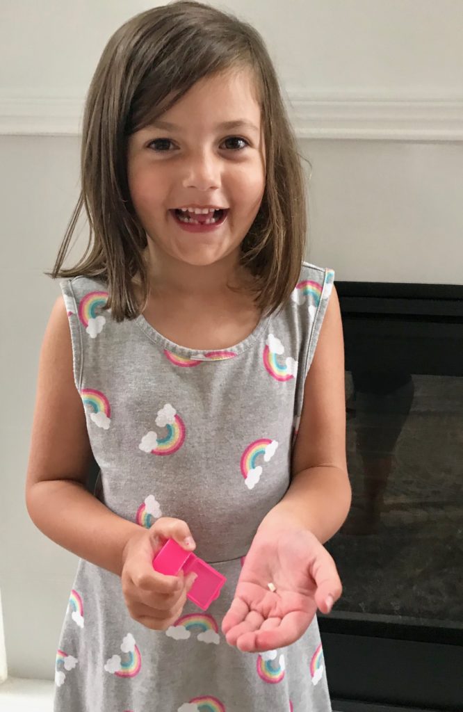 little girl holding pulled tooth